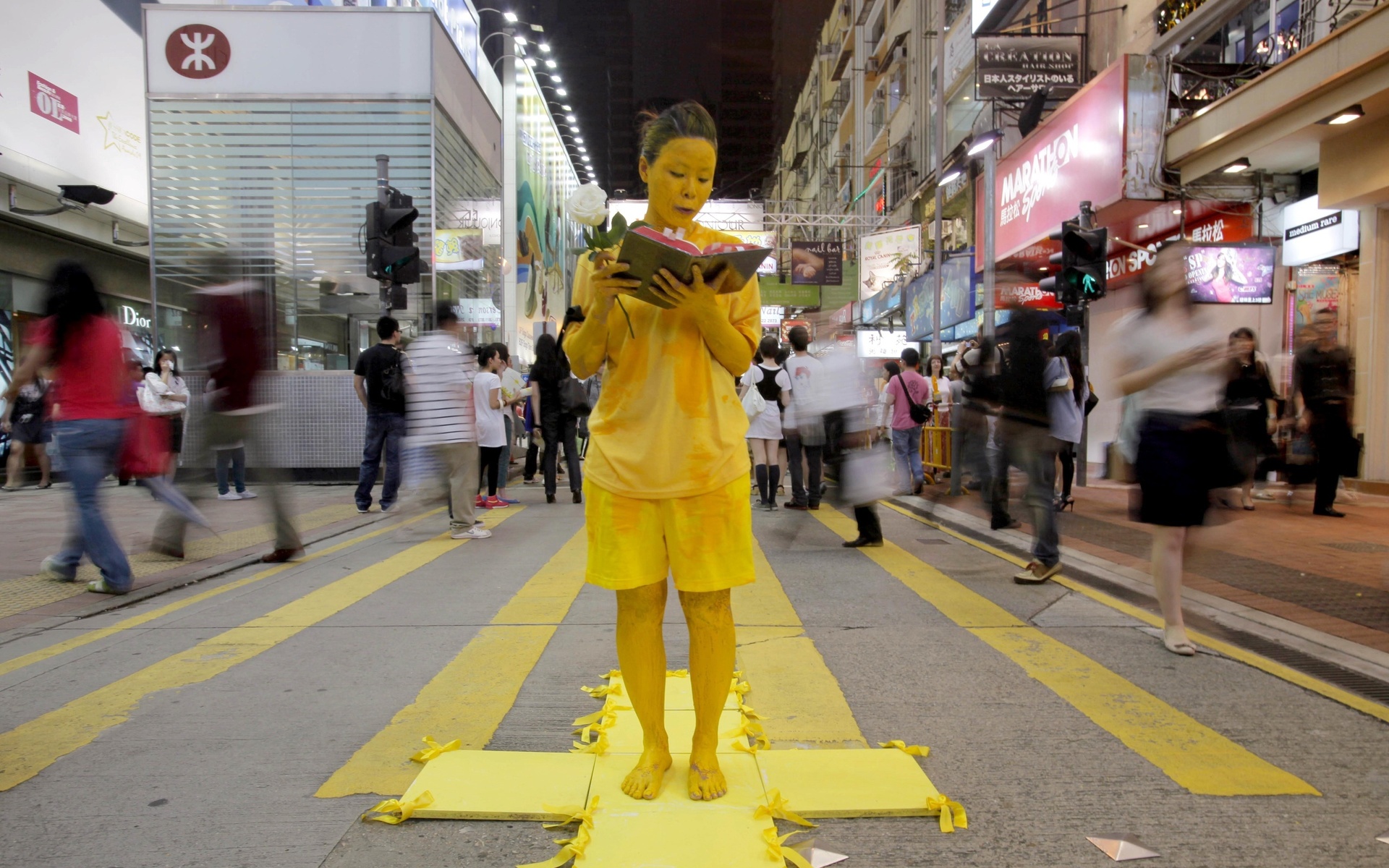 Artist Rachel Wong, who appears in yellow paint, reads a Bible to mark the 20th anniversary of the military crackdown on a pro-democracy student movement in Beijing Wednesday, June 3, 2009, in Hong Kong. Wong is part of a group of young artists who painted their bodies yellow as a means of representing the skin color of Chinese and to also symbolize freedom. (AP Photo/Kin Cheung)